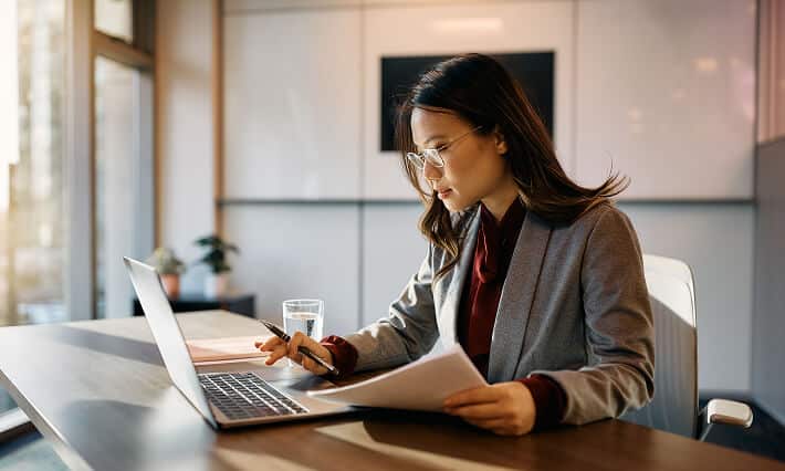 Businesswoman with brown hair working on a computer in an office.