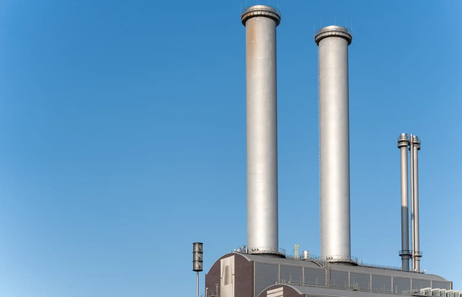 Industrial facility smokestacks against a clear blue sky