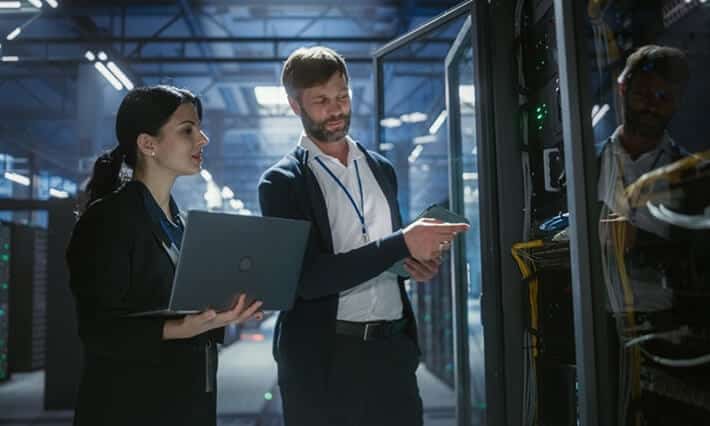 Two technicians inspecting server rack equipment in data center
